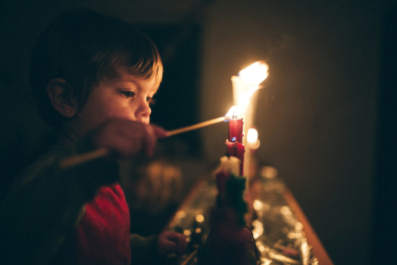 Poika sytyttämässä kynttilää.