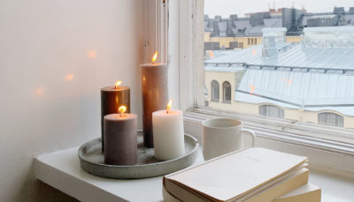 Joutsenmerkittyjä kynttilöitä, kahvikuppi ja kirjoja ikkunalaudalla Helsingissä. Kuva: Sara Peltola 2021